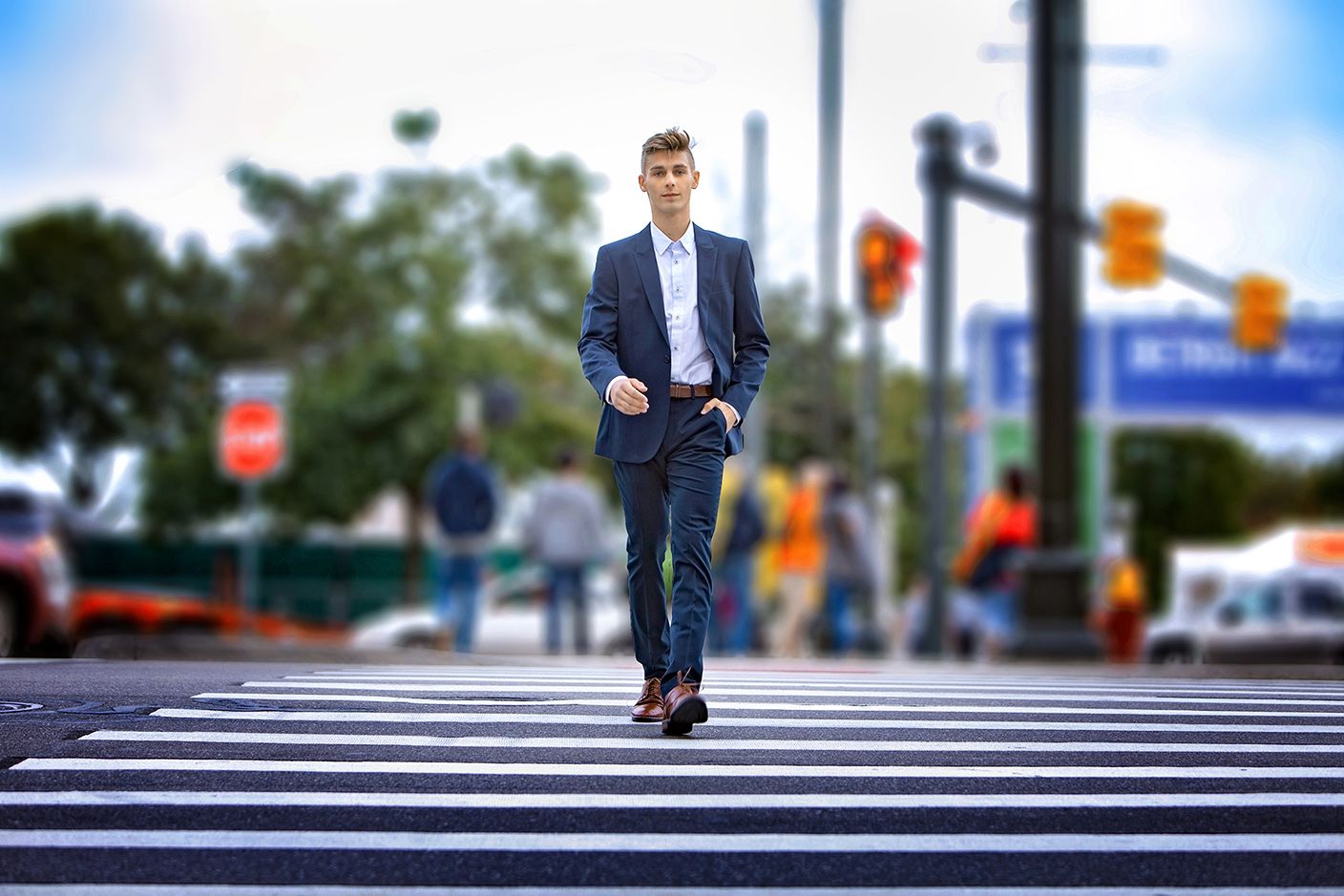Signature senior session in Rochester, MI by Jocelyn M. Photography—young man in a navy suit walking across a crosswalk.
