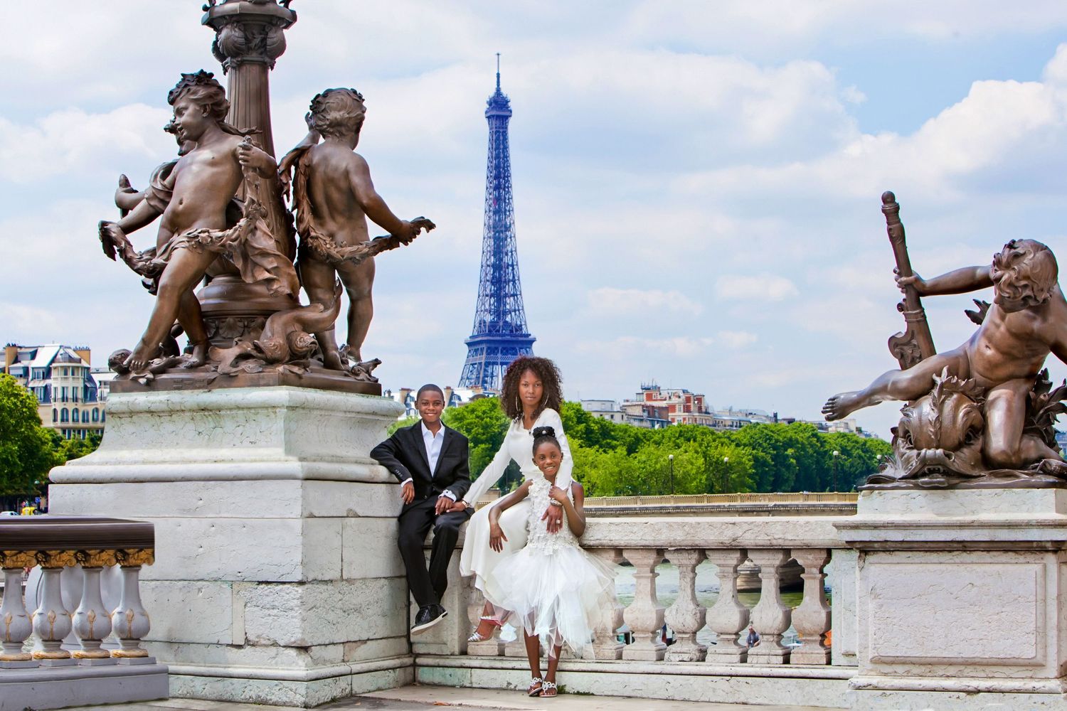 Couple in wedding attire posing on Pont Alexandre III bridge with Eiffel Tower in background, Paris.