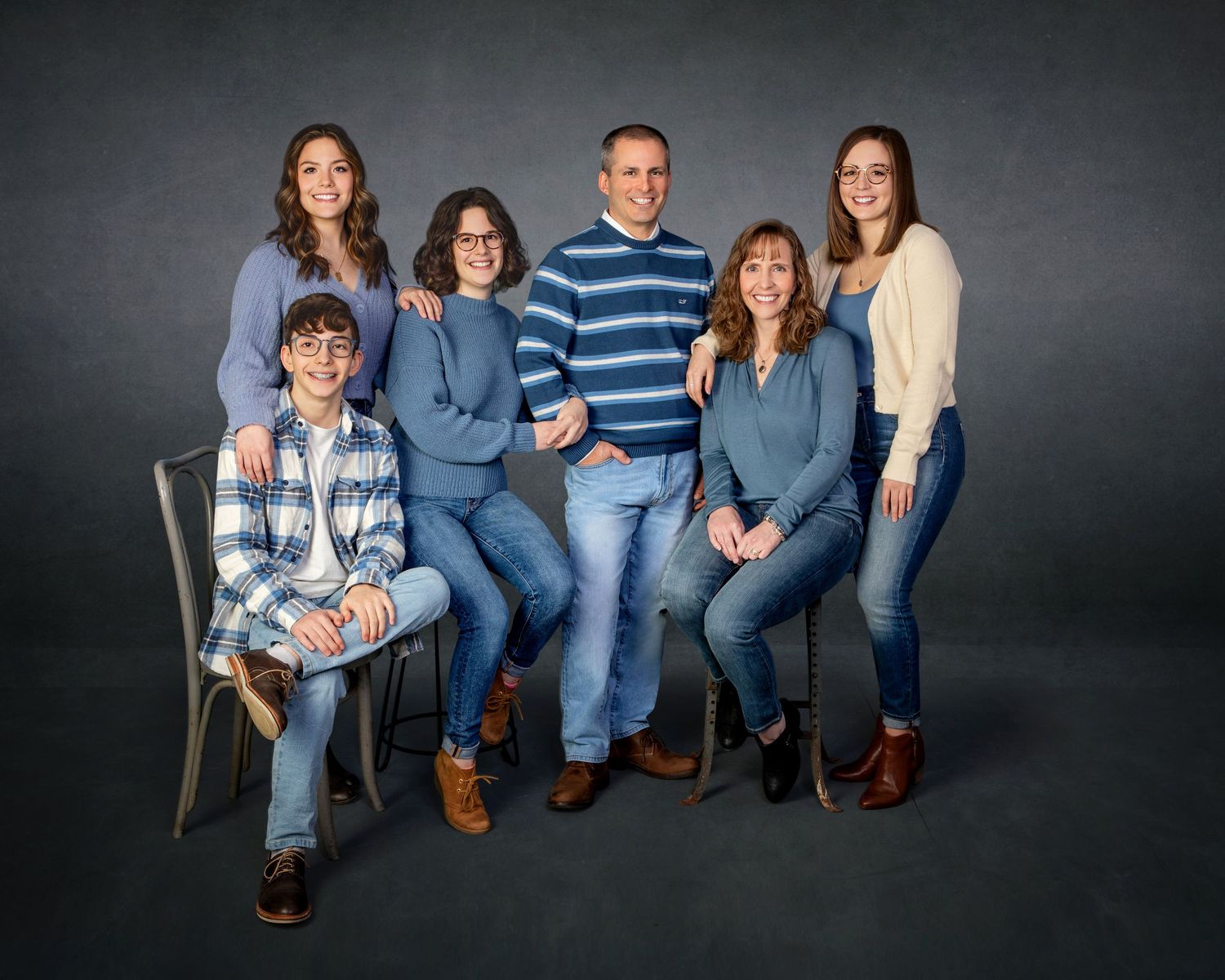 Family of six posing together in coordinating blue outfits for a professional studio portrait photo.