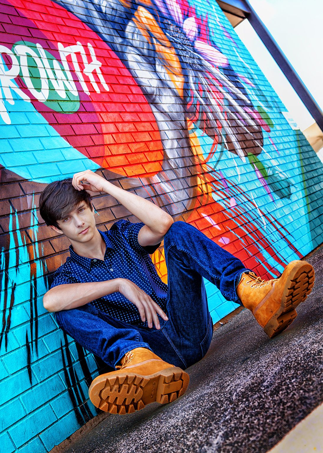 Urban senior portrait session in Rochester, MI by Jocelyn M. Photography—teen boy posing by a colorful graffiti mural.