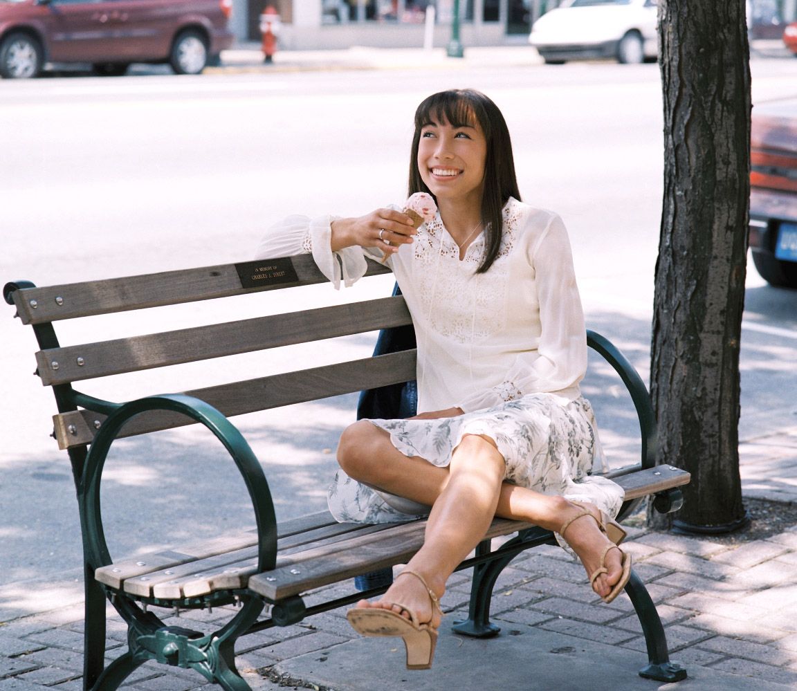 Senior girl sitting on a park bench outdoors, smiling on a sunny day by Jocelyn M. Photography in Rochester, MI,