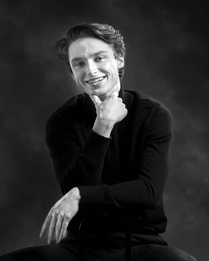 Black and white senior portrait in Rochester, MI by Jocelyn M. Photography—young man in black turtleneck on dark backdrop. (