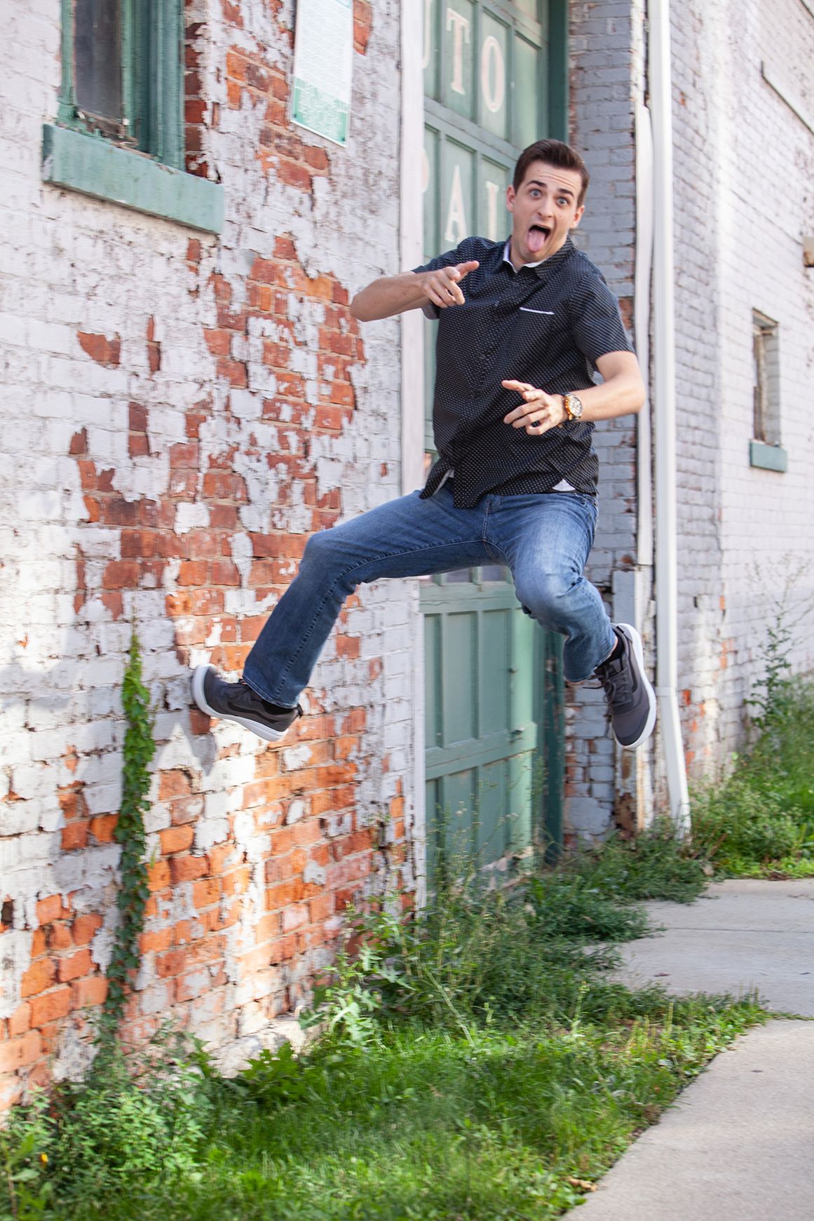 Senior portrait for guys in Rochester, MI by Jocelyn M. Artistic Photography—young man jumping by a brick building.