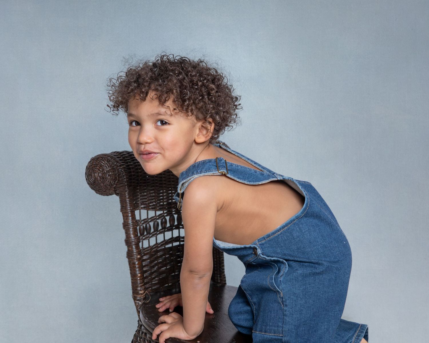 2-year-old child milestone session in Rochester, MI by Jocelyn M. Photography—curly-haired boy in denim overalls.
