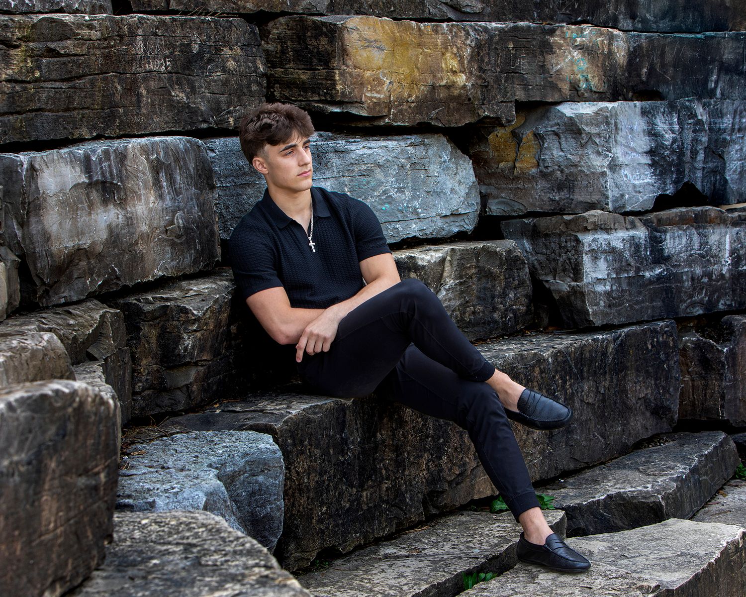Outdoor high school senior session in Rochester, MI by Jocelyn M. Photography—young man posing on rocky stone steps.