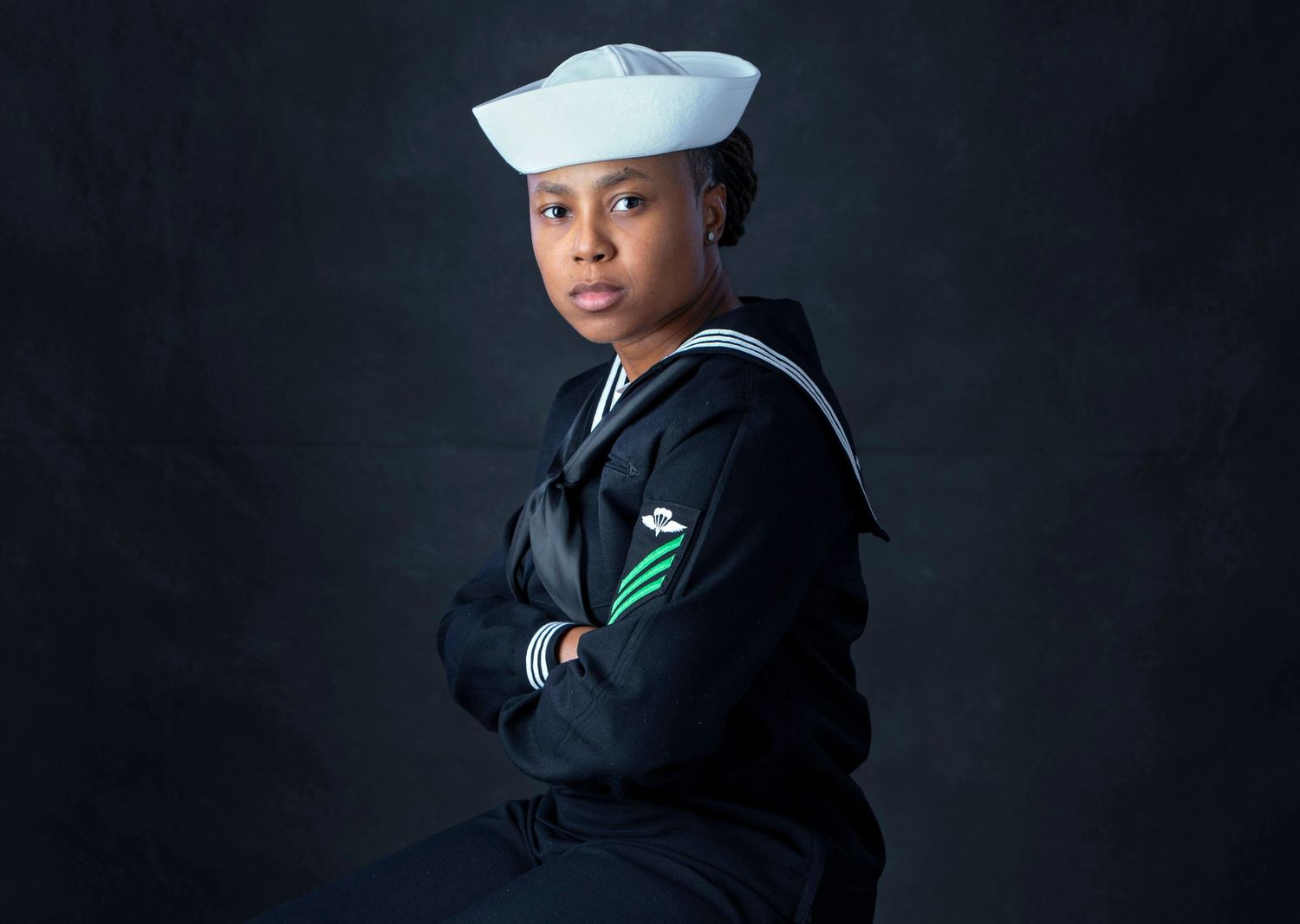 Young woman in Navy uniform poses confidently with arms crossed for military portrait.