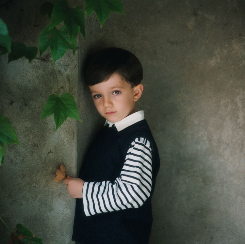 Milestone children's portrait in Rochester, MI by Jocelyn M. Photography—young boy leaning against a stone wall.