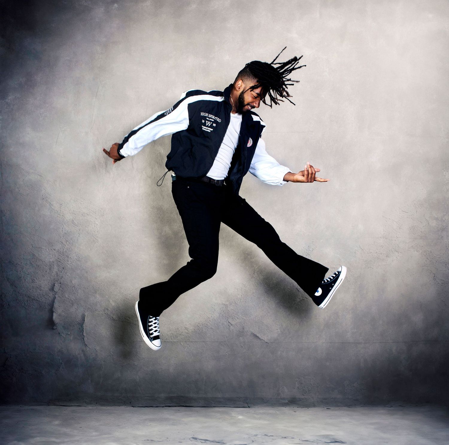 Action senior portrait session in Rochester, MI by Jocelyn M. Photography—young man jumping against a gray wall.