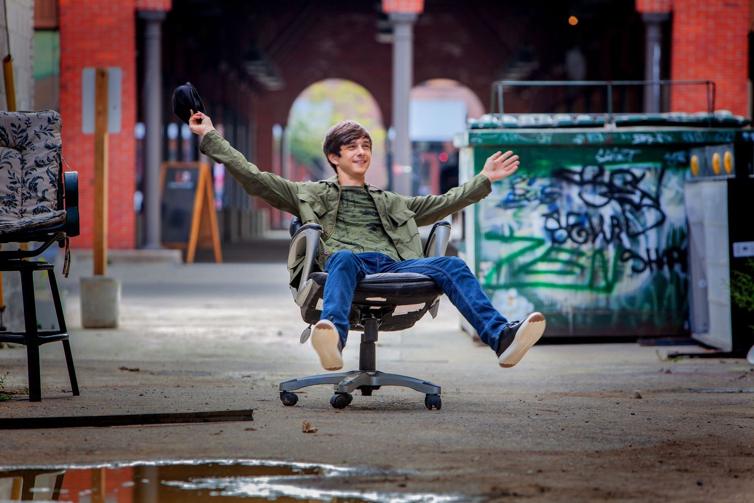 Fun high school senior portrait in Rochester, MI by Jocelyn M. Photography—young man riding an office chair outdoors.