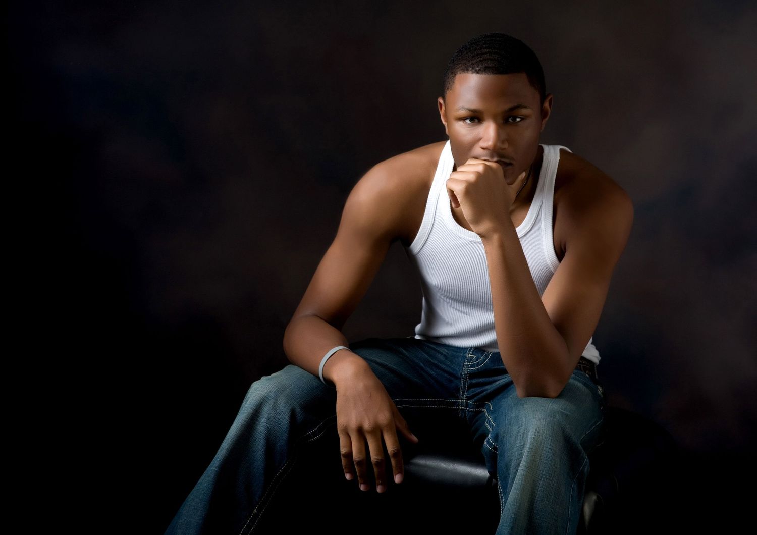 Senior portrait for guys in Rochester, MI by Jocelyn M. Photography—young man sitting thoughtfully in studio.