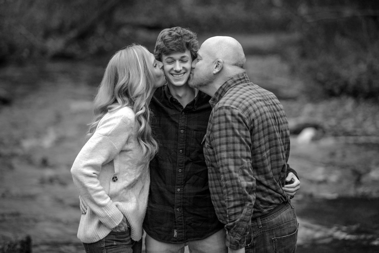 Senior family portrait in Rochester, MI by Jocelyn M. Photography—black and white photo of parents kissing senior son.