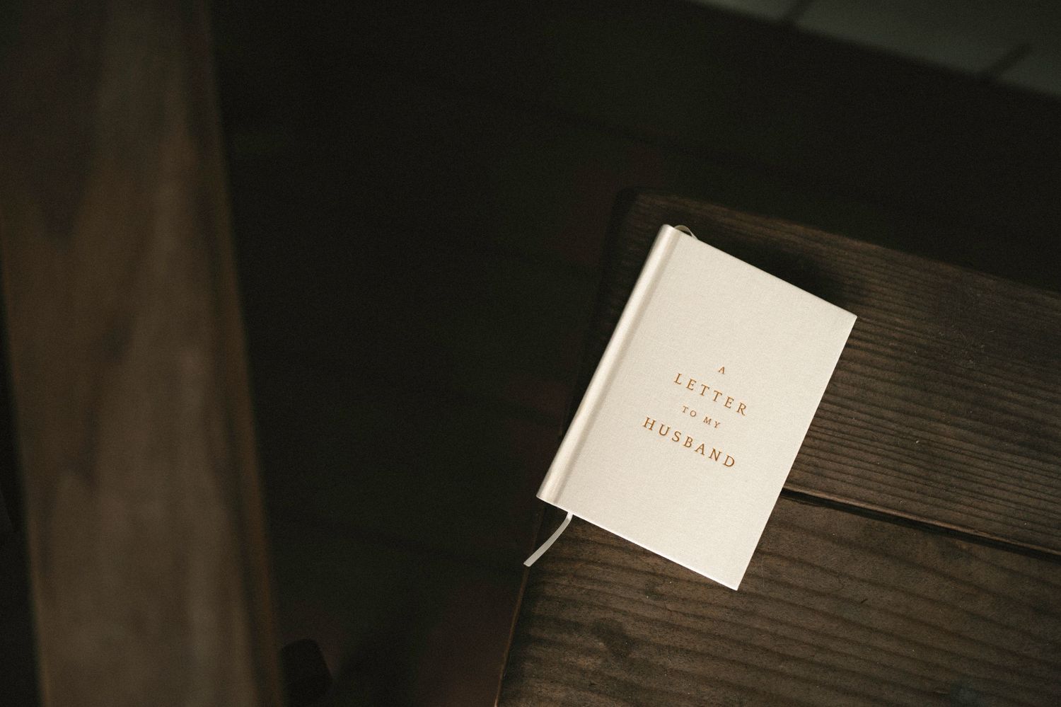 White hardcover book titled 'A Letter to My Husband' resting on a dark wooden surface.
