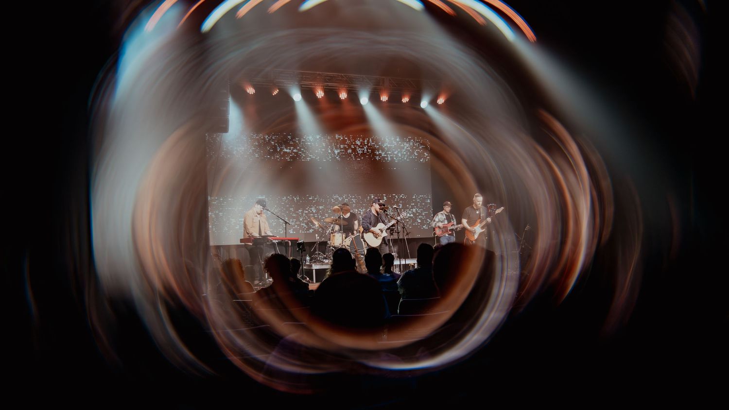 Abstract blurred motion effect creates a swirling pattern in dark tones with hints of light streaking through.
