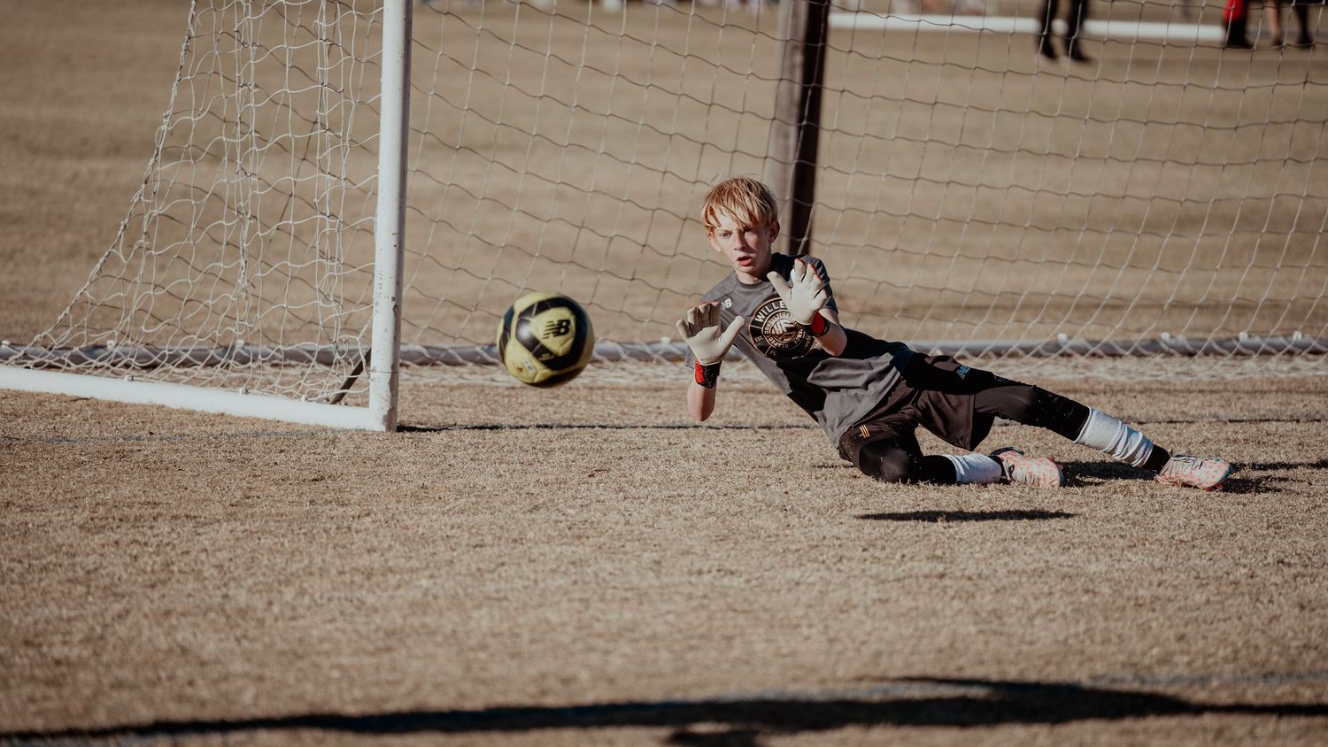 A sequence of soccer action shots showing a goalkeeper diving to make a dramatic save during a match.