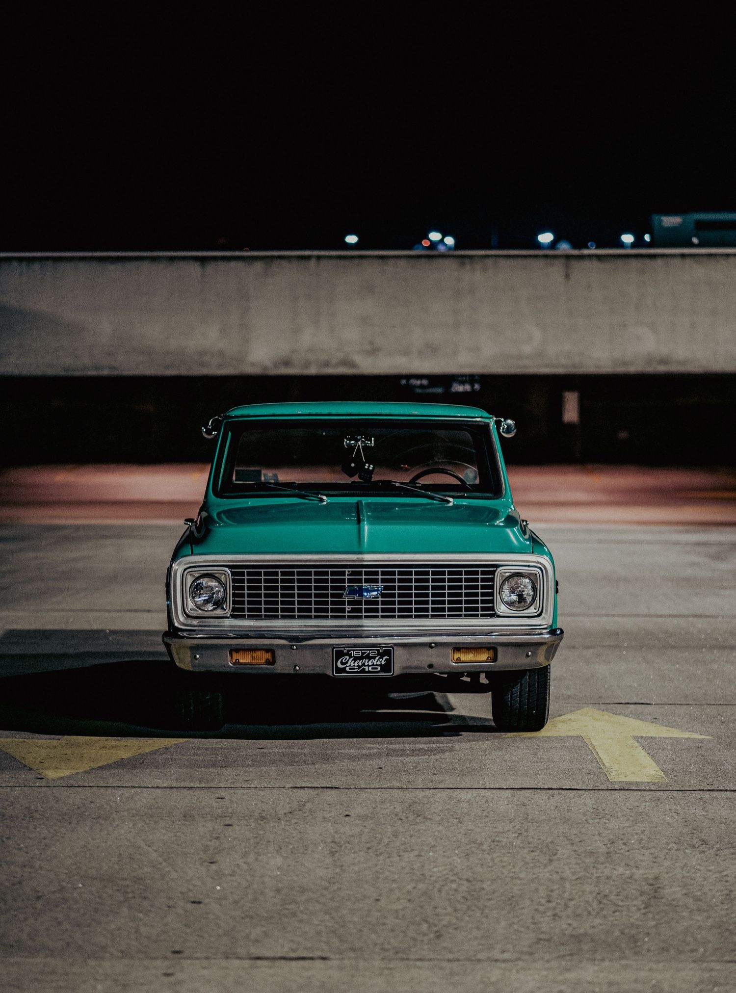 Vintage turquoise Chevrolet C10 pickup truck parked in a dimly lit concrete parking structure.