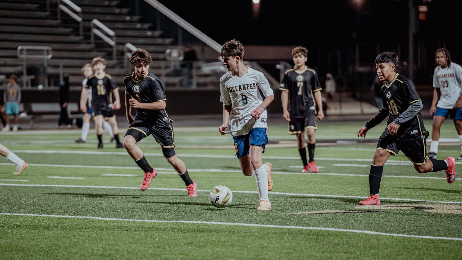 Soccer players compete for the ball on an artificial turf field during an intense match.