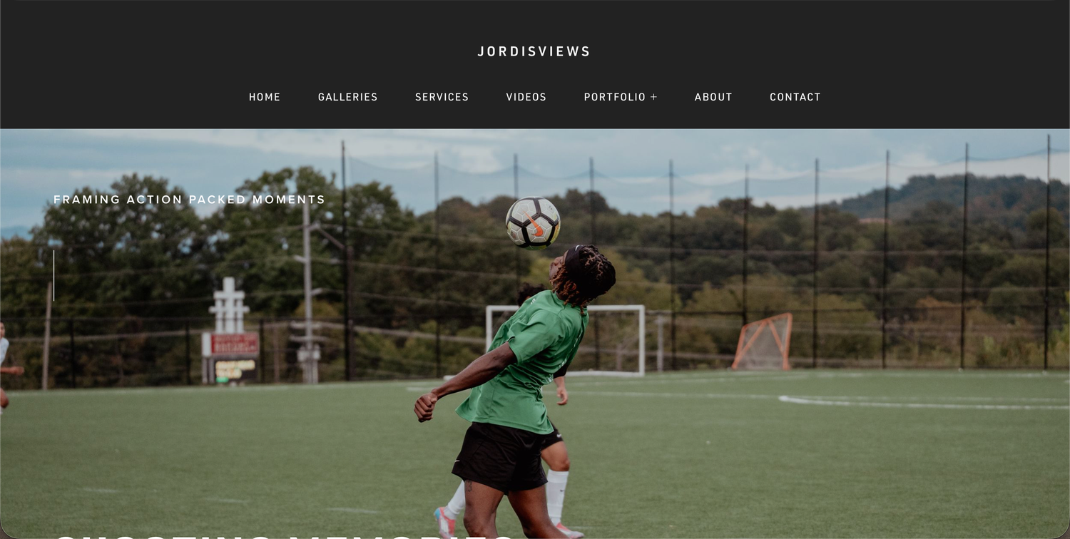 Soccer player in green jersey kicks ball on artificial turf field with goal posts and trees in background.