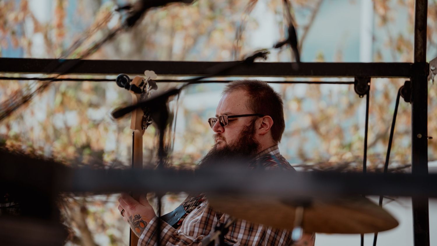 Drummer with glasses behind drum set cymbals performs during golden hour.