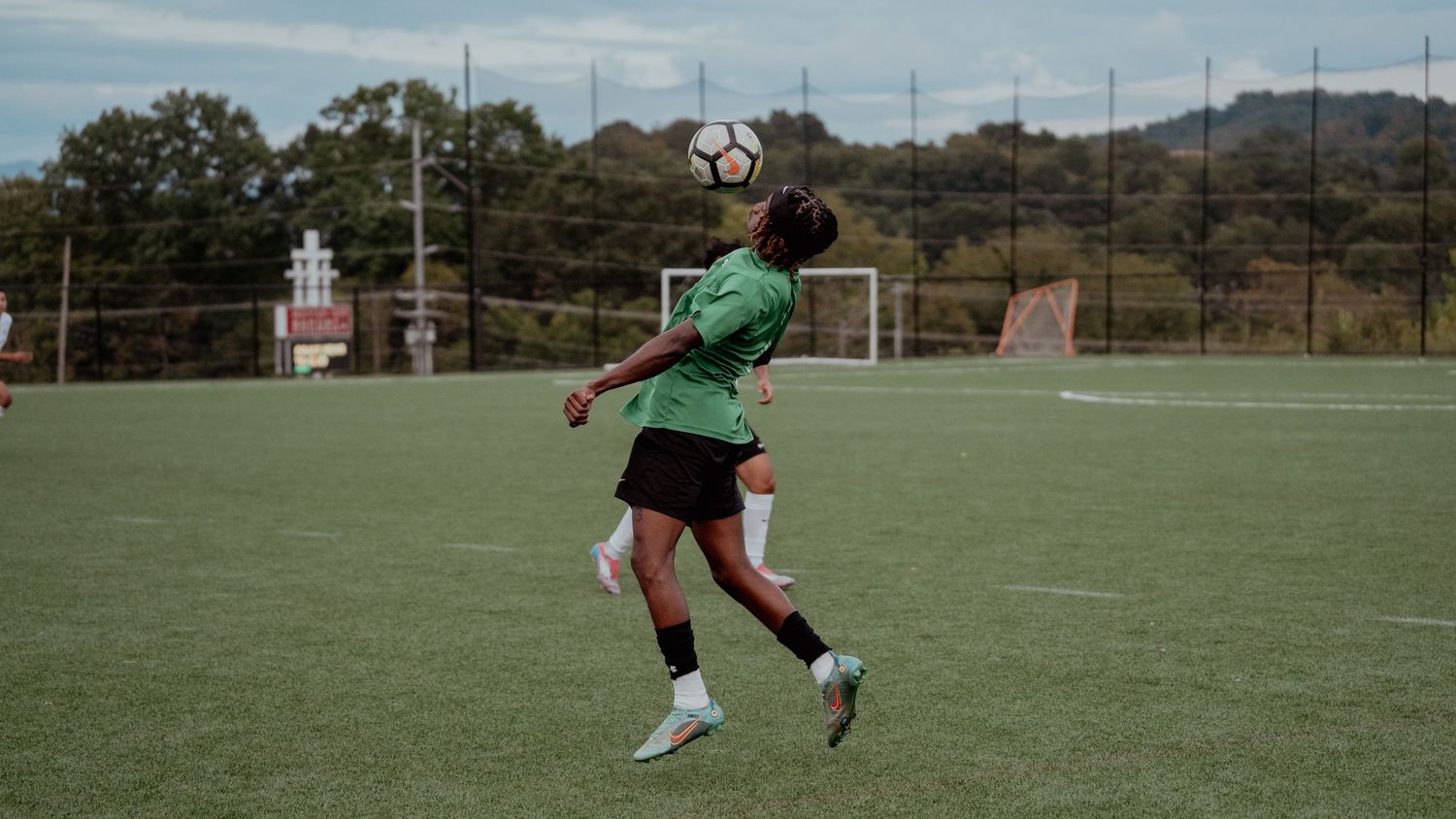 Soccer players compete for possession of the ball during an intense match on a green grass field.