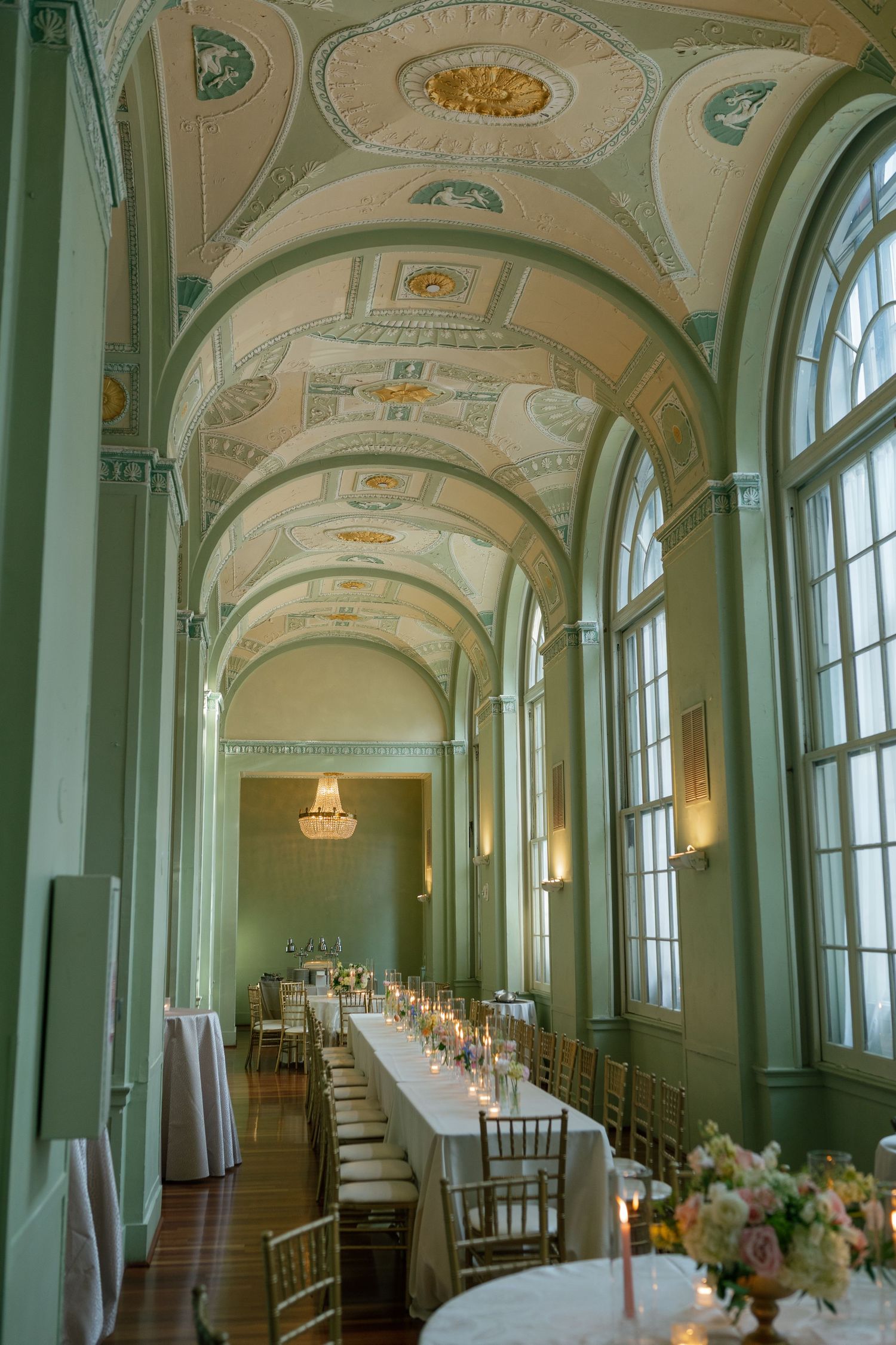 Elegant ballroom with arched ceilings, tall windows, and long banquet tables set for a formal dining event.
