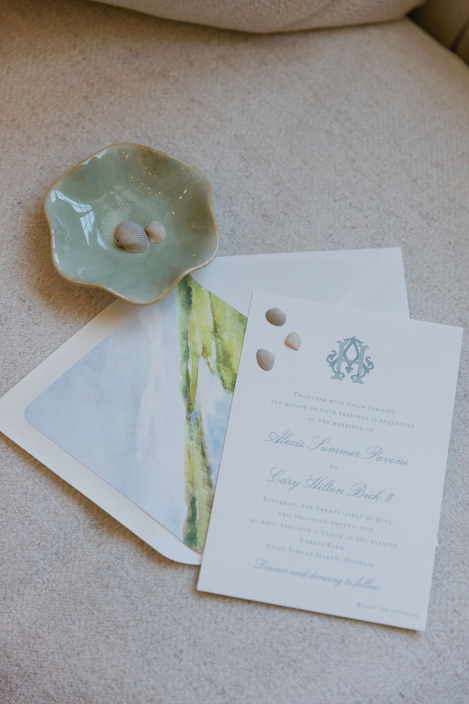 Wedding invitation cards with watercolor details in soft blue and green tones displayed on a light surface.