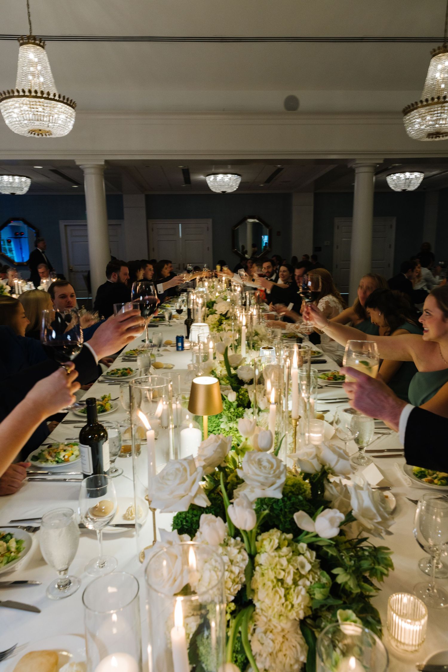 Elegant wedding reception tables decorated with white floral centerpieces, glowing candles and crystal glassware.