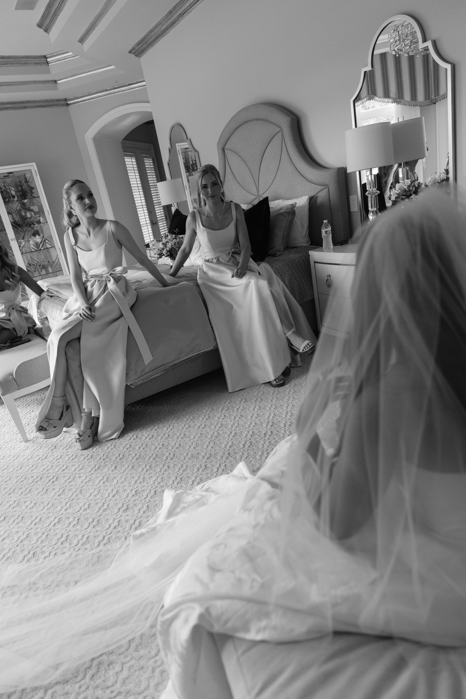 A series of black and white photos showing a wedding dress being fitted and arranged in an elegant room.