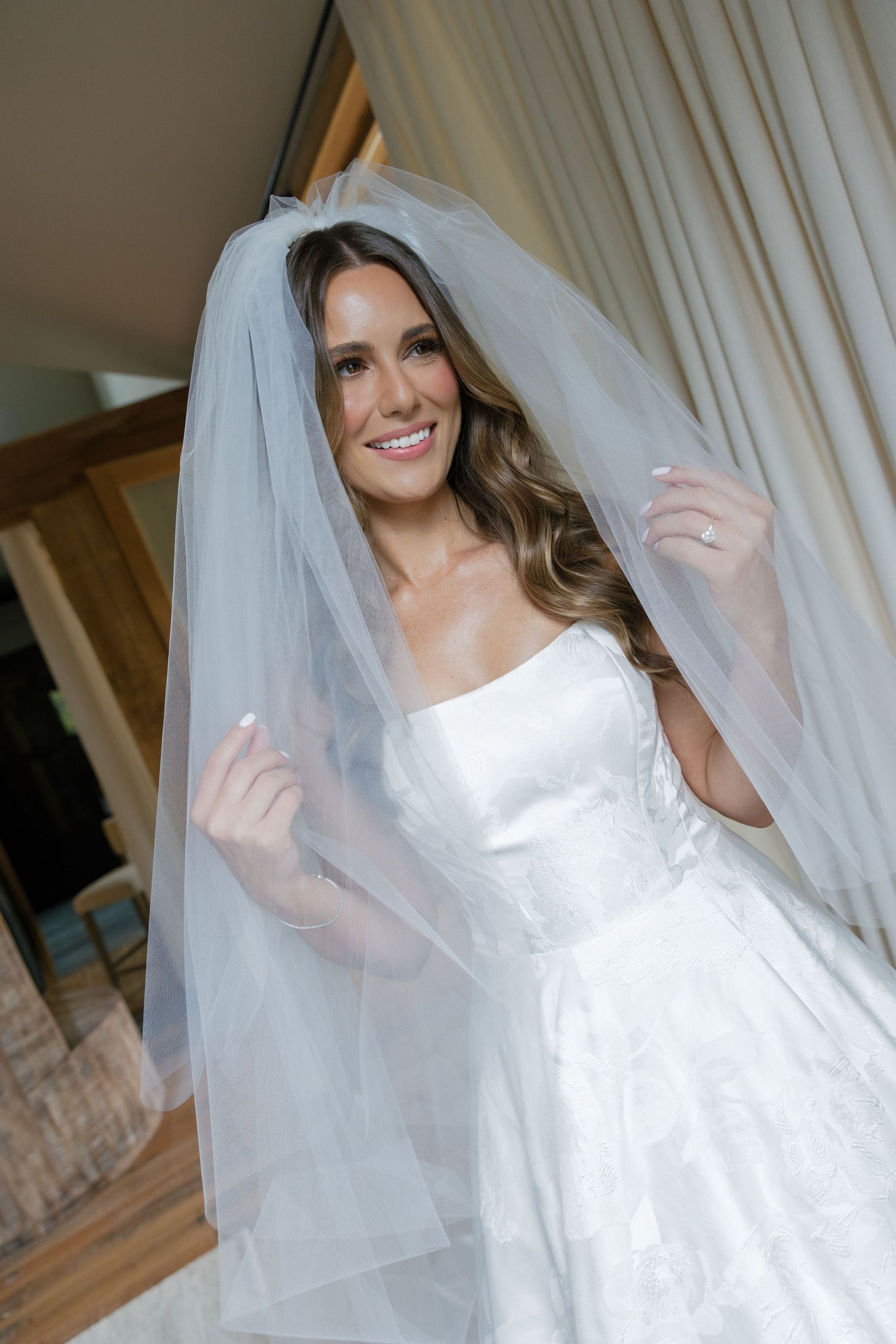 A bride in a white wedding dress and veil poses playfully behind sheer curtains in a series of photos.