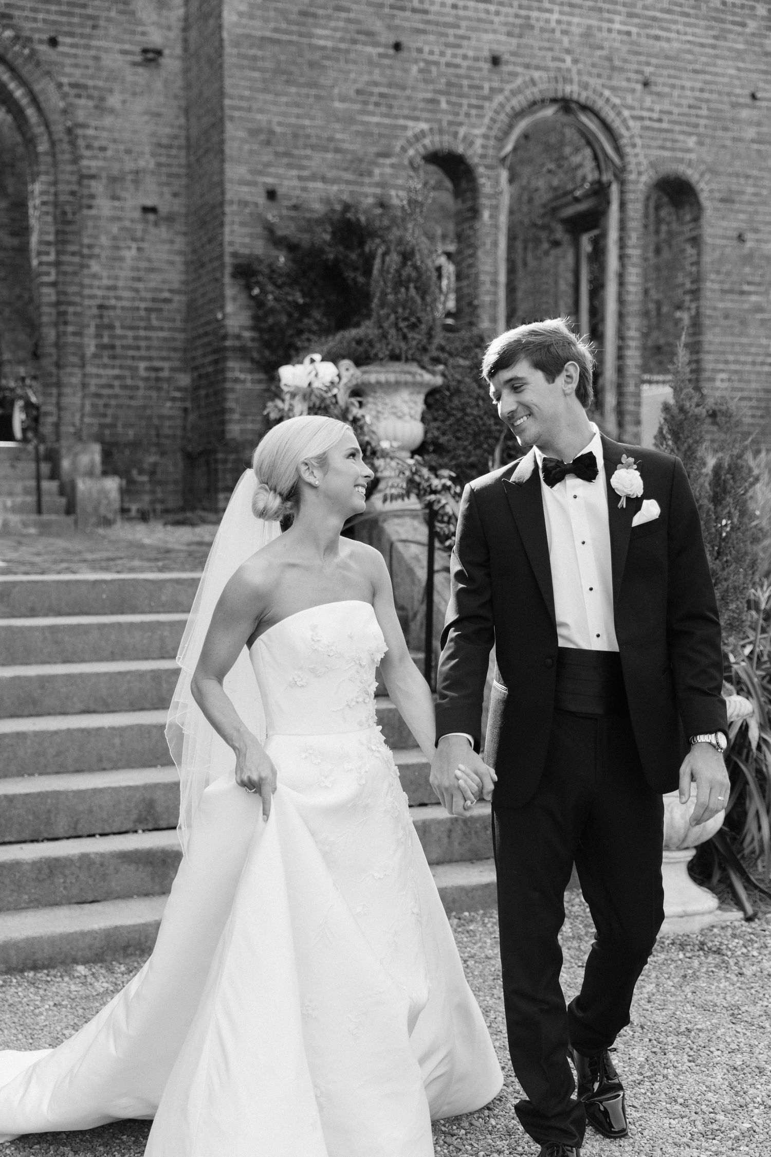 A sequence of black and white wedding photos showing a couple in formal attire interacting playfully on stone steps.