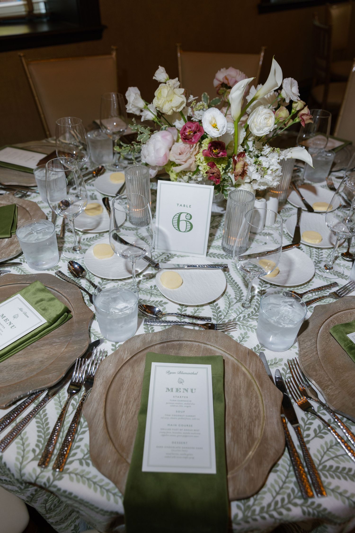 Elegant wedding reception table settings with white linens, floral centerpieces, and menu cards in a formal dining arrangement.