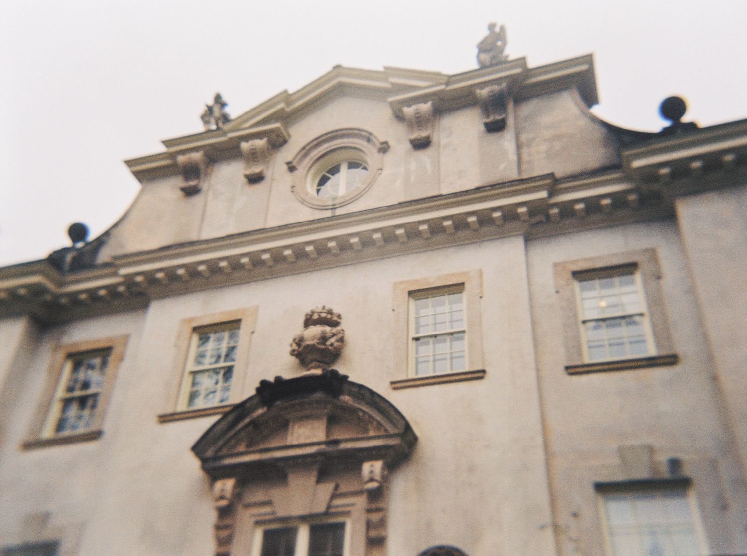 Ornate cream-colored building facade with Georgian architectural features and decorative stone statues on the top ledge. swann house