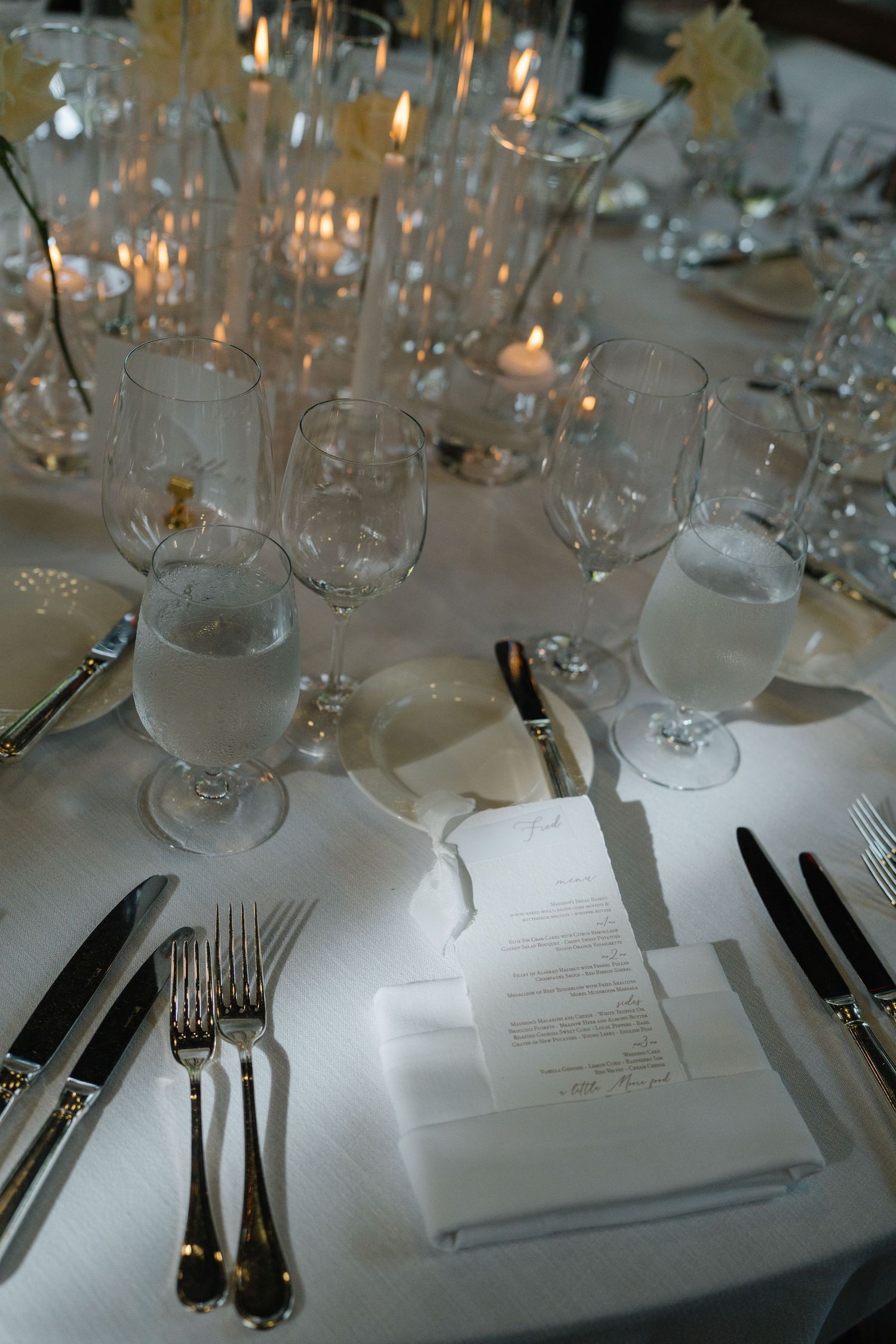Elegant table settings at a formal dinner with glassware, silverware, and menu cards on crisp white linens.