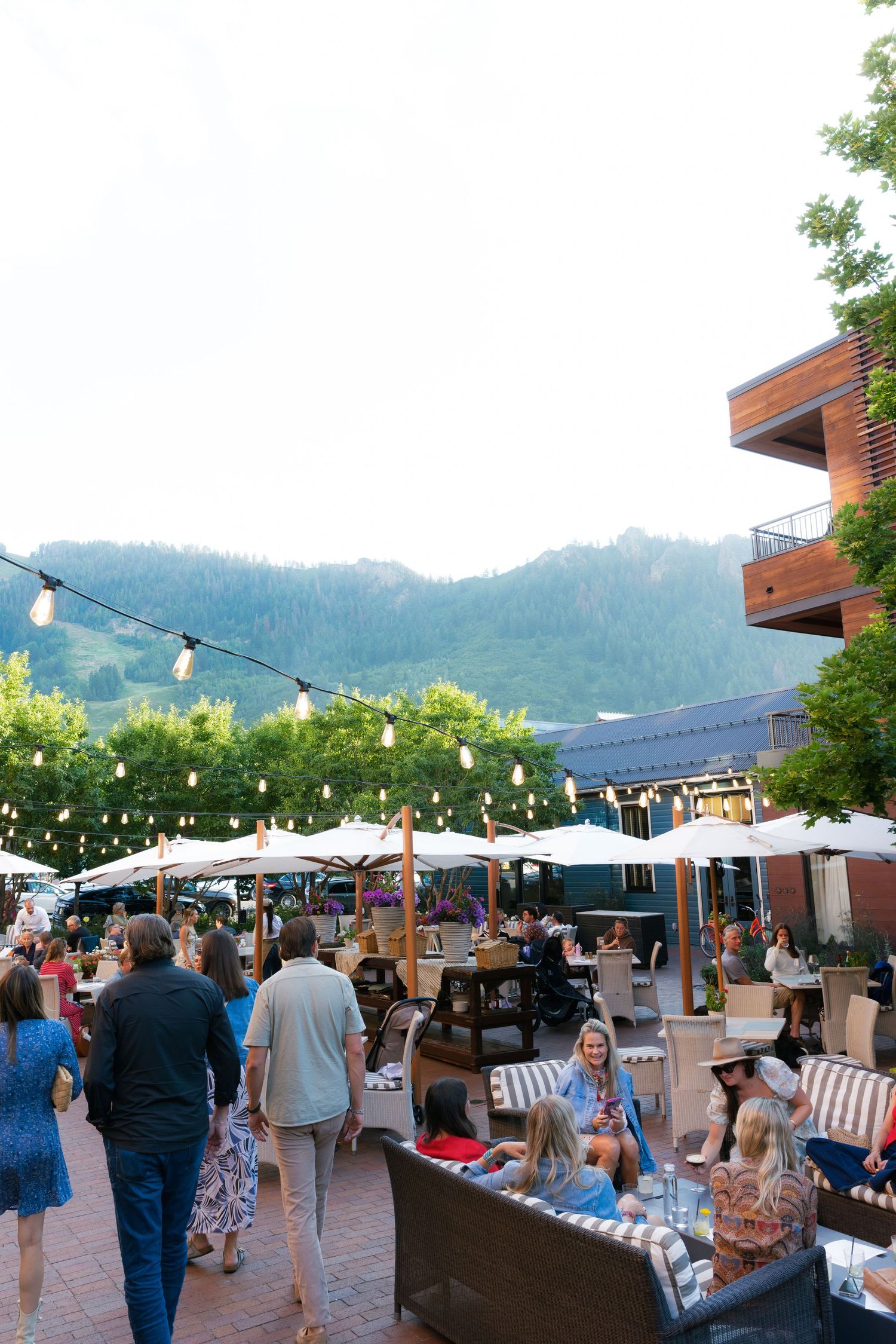 Outdoor evening market with string lights and vendor booths set against mountain backdrop.