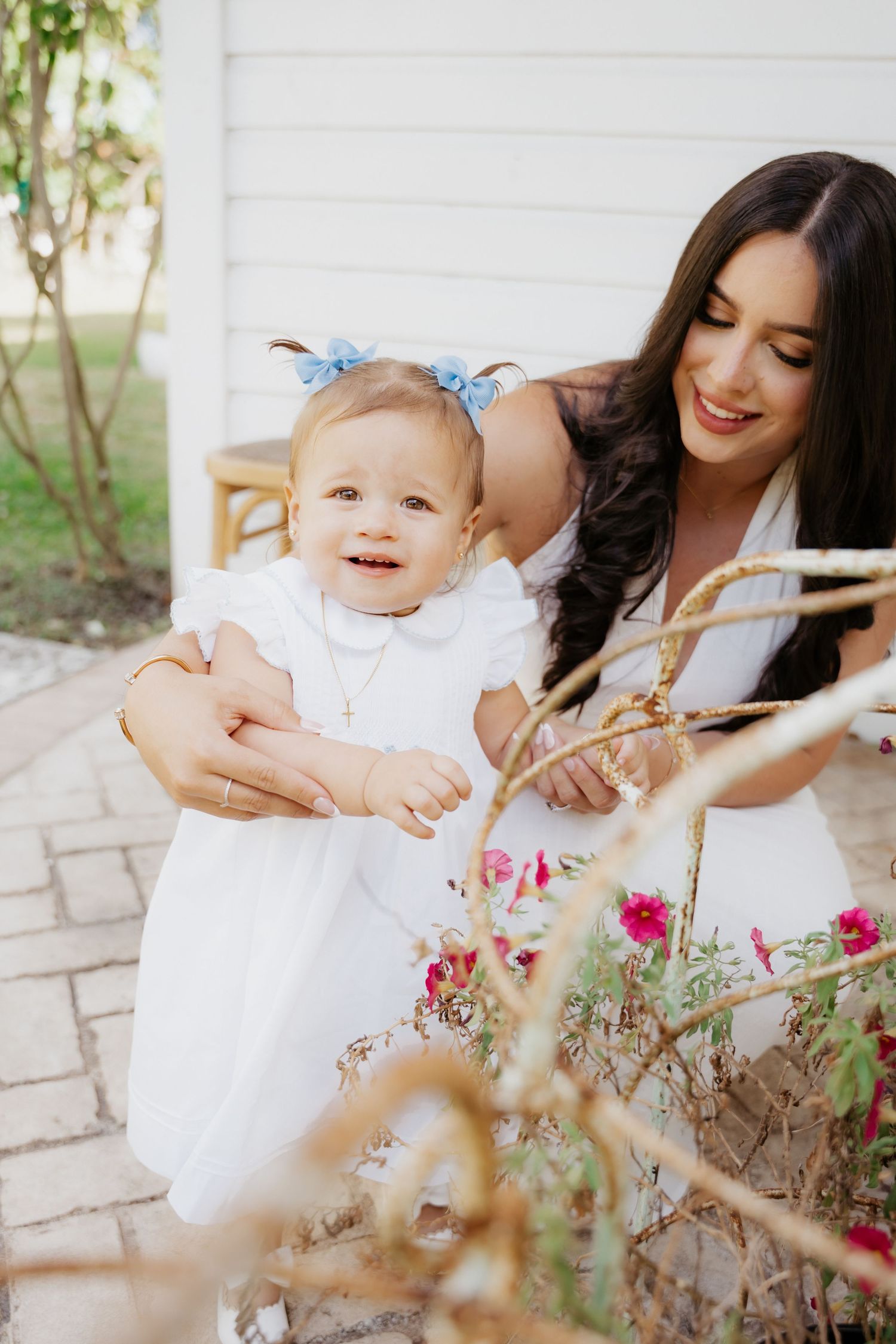 Mother smelling flowers with toddler during candid motherhood photo session in Miami, FL.