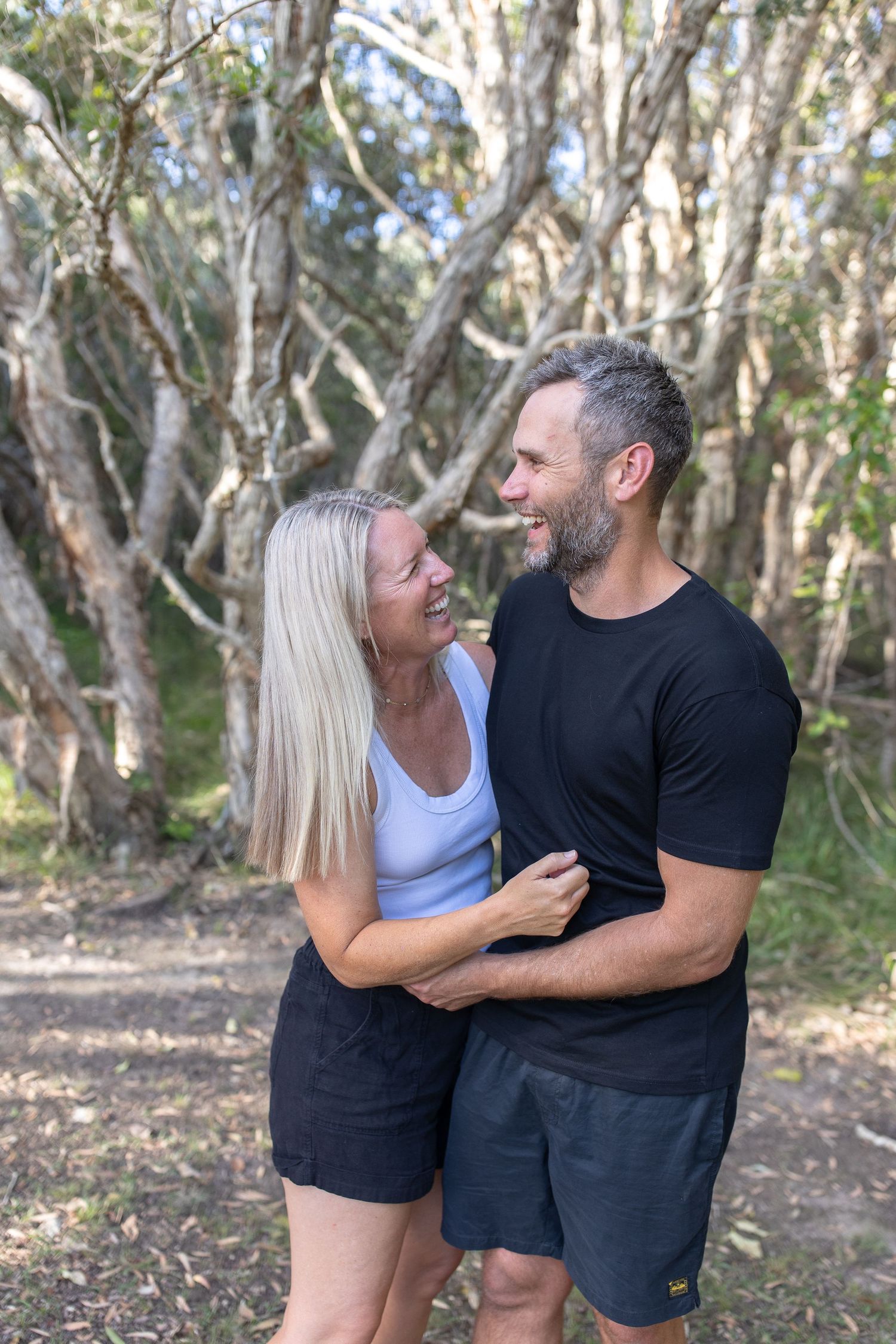Couple sharing intimate moments and laughter in a forest setting.
