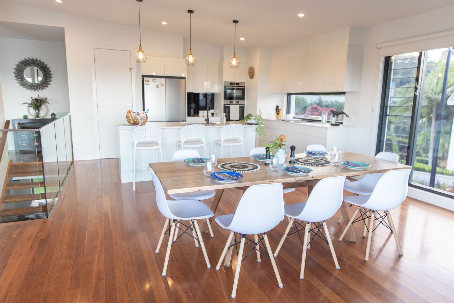 Open concept dining and kitchen area with white chairs and hardwood flooring.