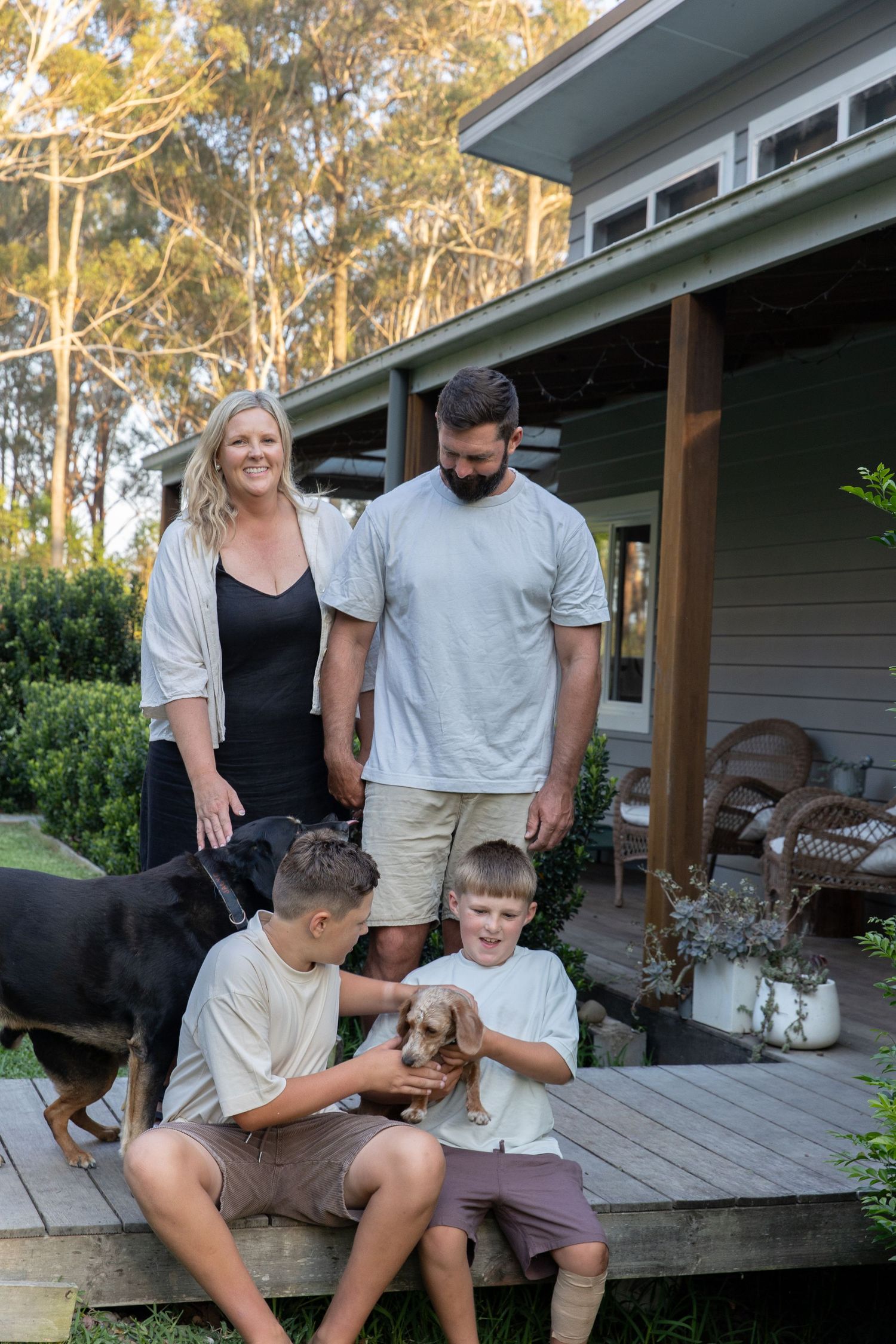 Family relaxes together on a wooden porch with their small dog.
