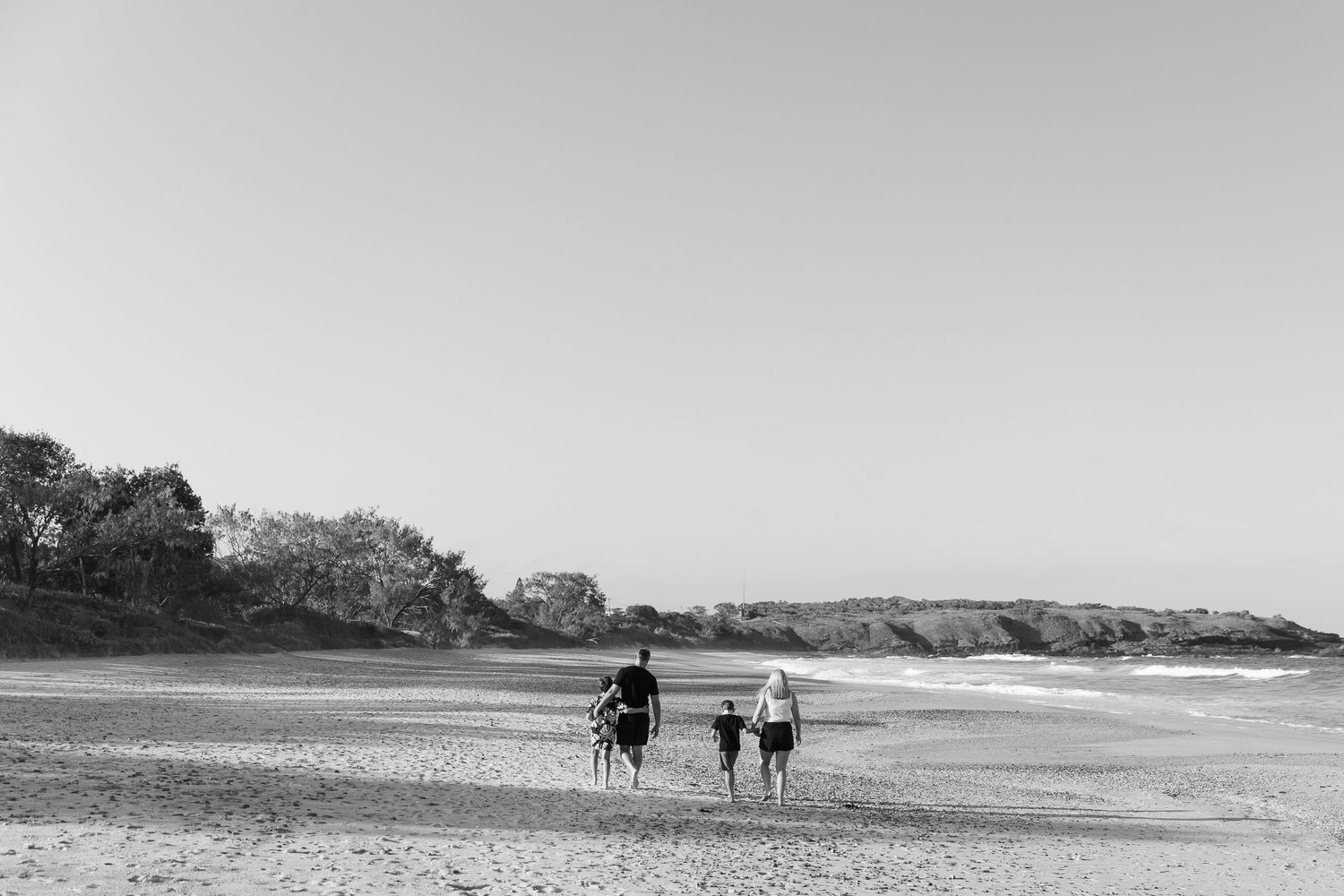 Wide panoramic view of a beach landscape with distant figures.