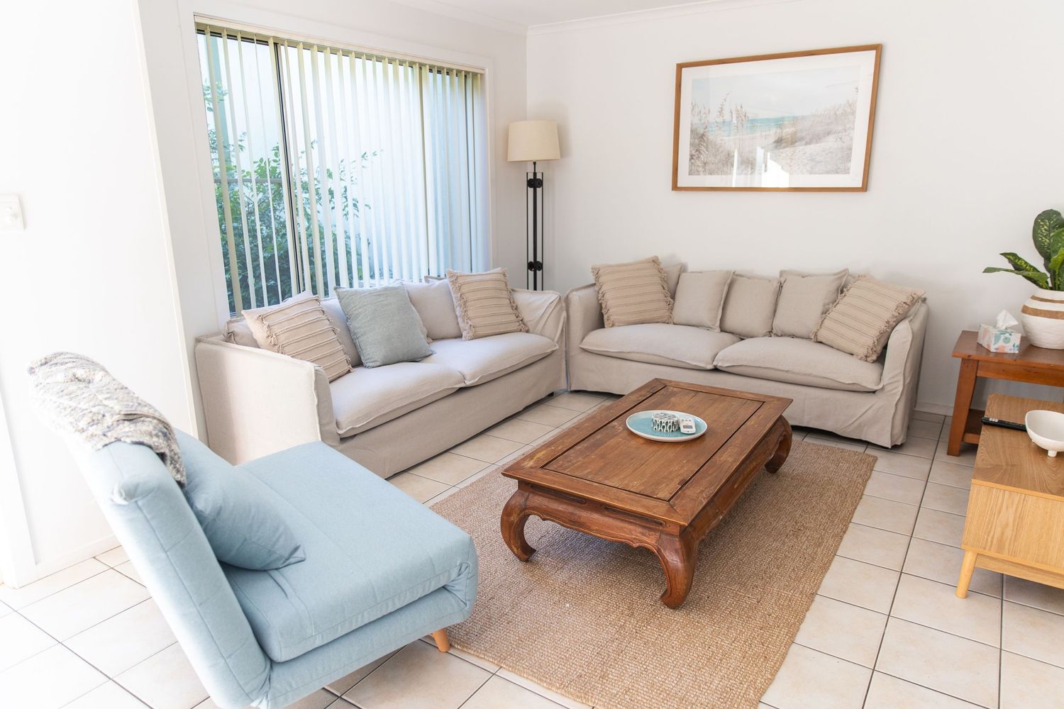 Coastal-style living room with light blue and beige furniture and natural lighting.