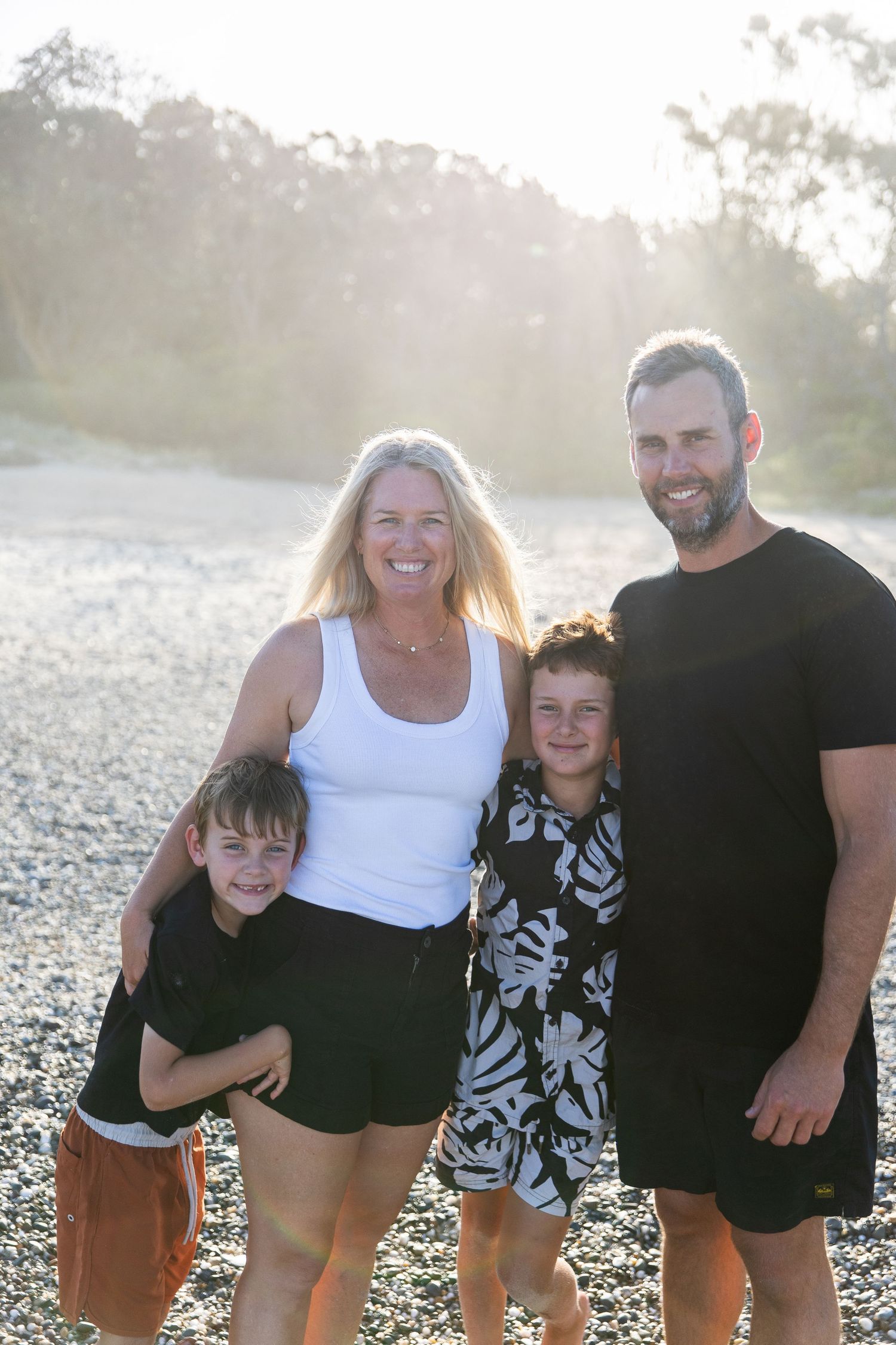 Family enjoying a candid moment together at sunset on a beach with laughter and smiles.