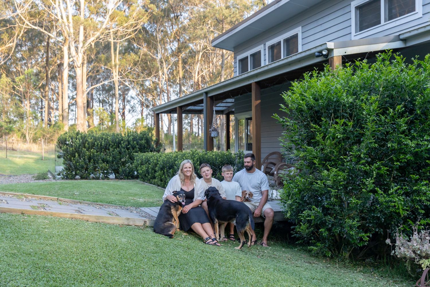 Wide view of a gray house with a covered porch surrounded by eucalyptus trees.