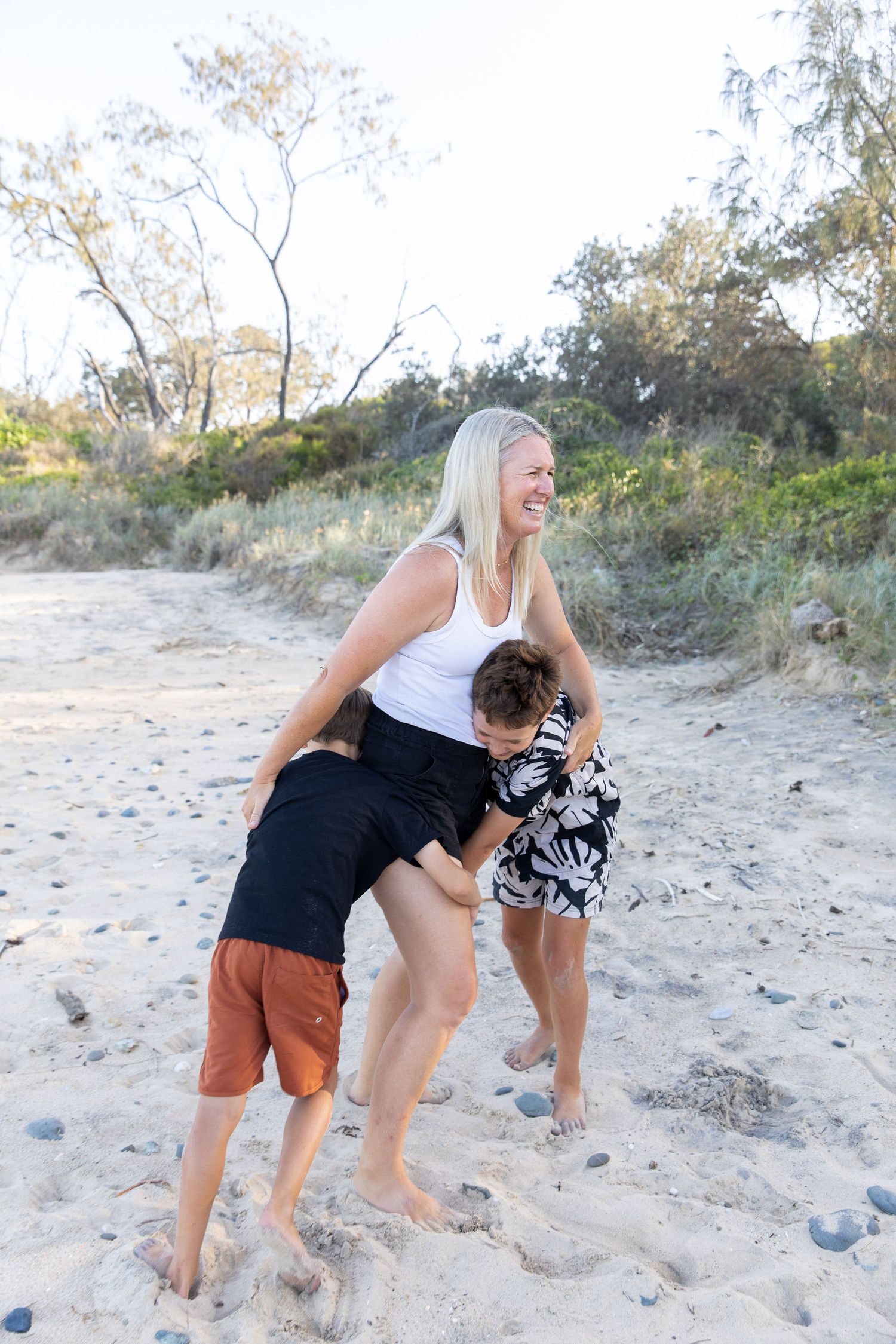 Family members playing and laughing together on a sandy beach.