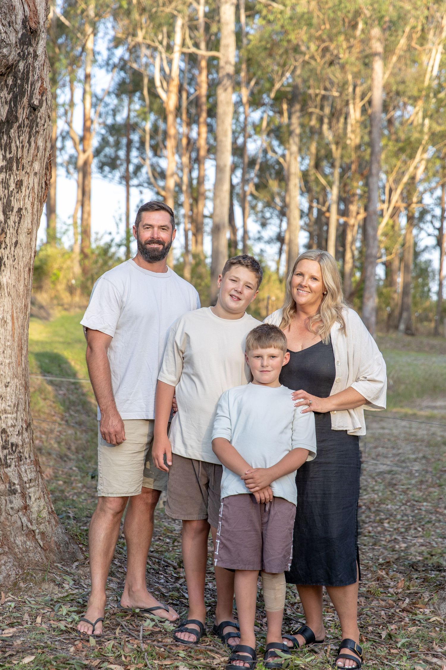 Family group poses together on a wooded hillside surrounded by tall eucalyptus trees.
