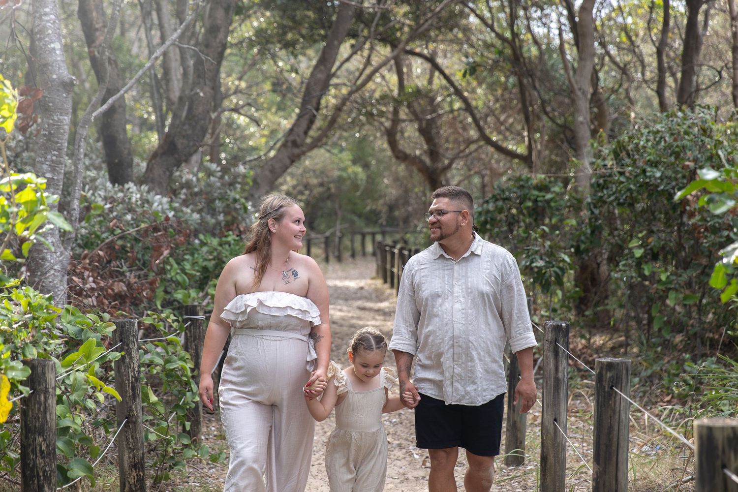 Family strolling together on a wooded path during an outdoor photo session.
