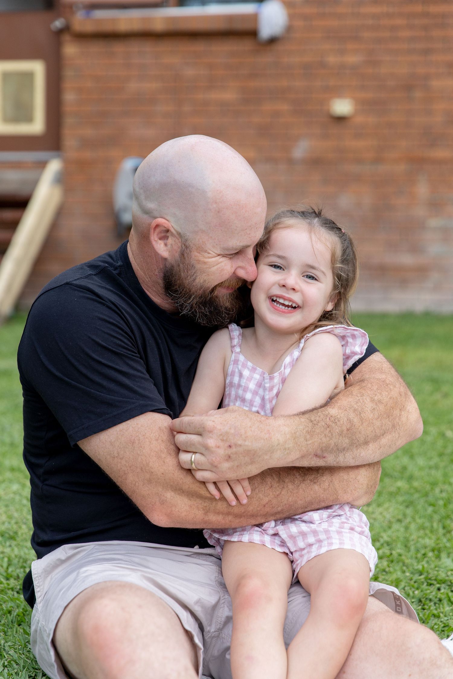 Joyful playtime moments shared on a lawn against a brick wall backdrop.