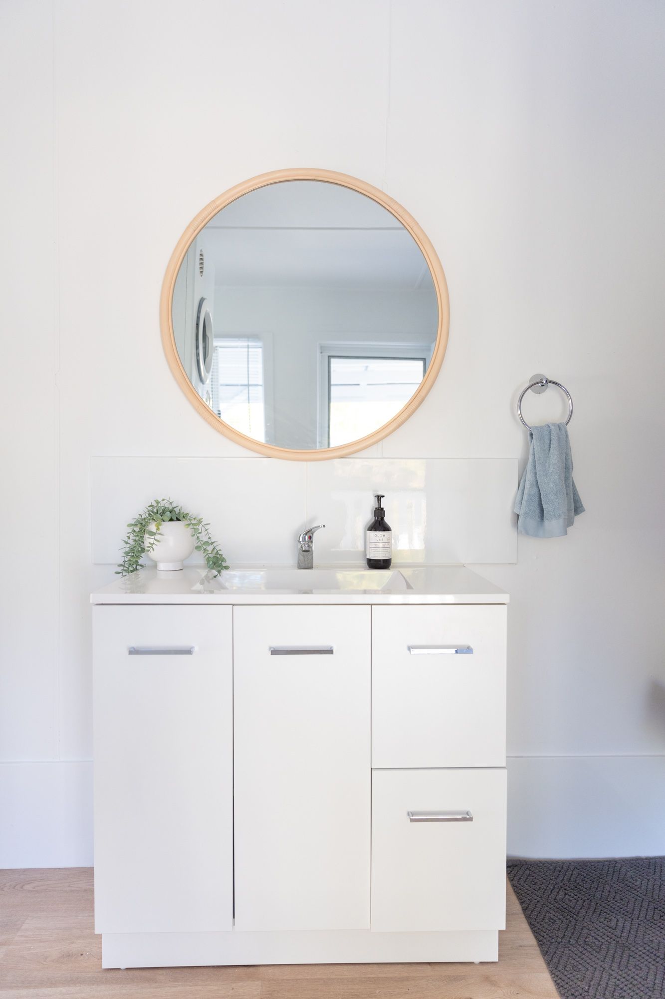 Modern white bathroom vanity with oval mirrors and minimalist design.