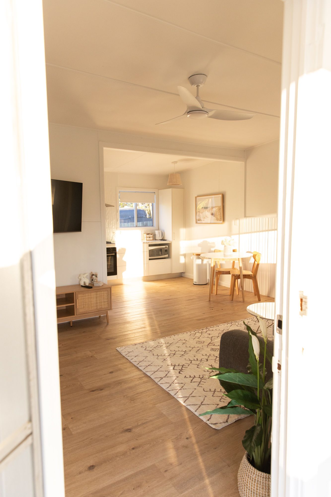 Open-concept living space with hardwood floors, ceiling fan, and natural lighting.