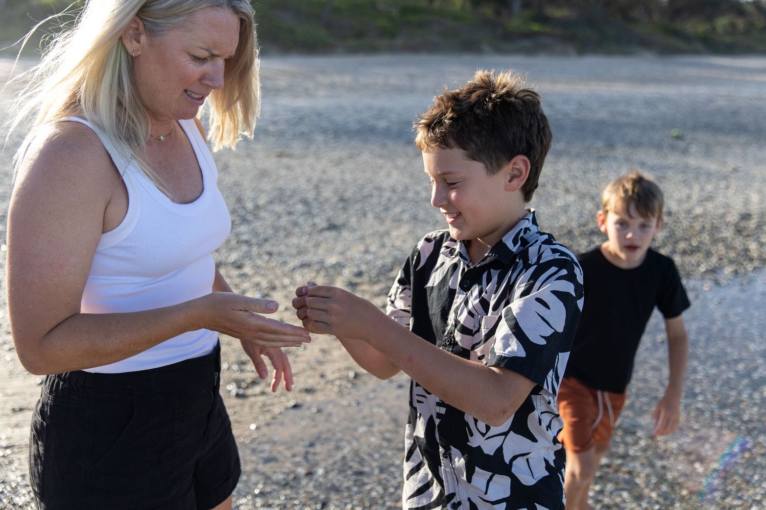 Family members interacting playfully on a rocky beach setting.