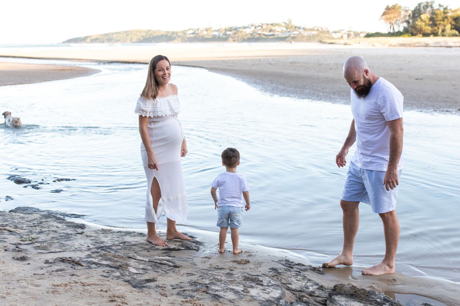 Family strolling along beach shoreline during golden hour.