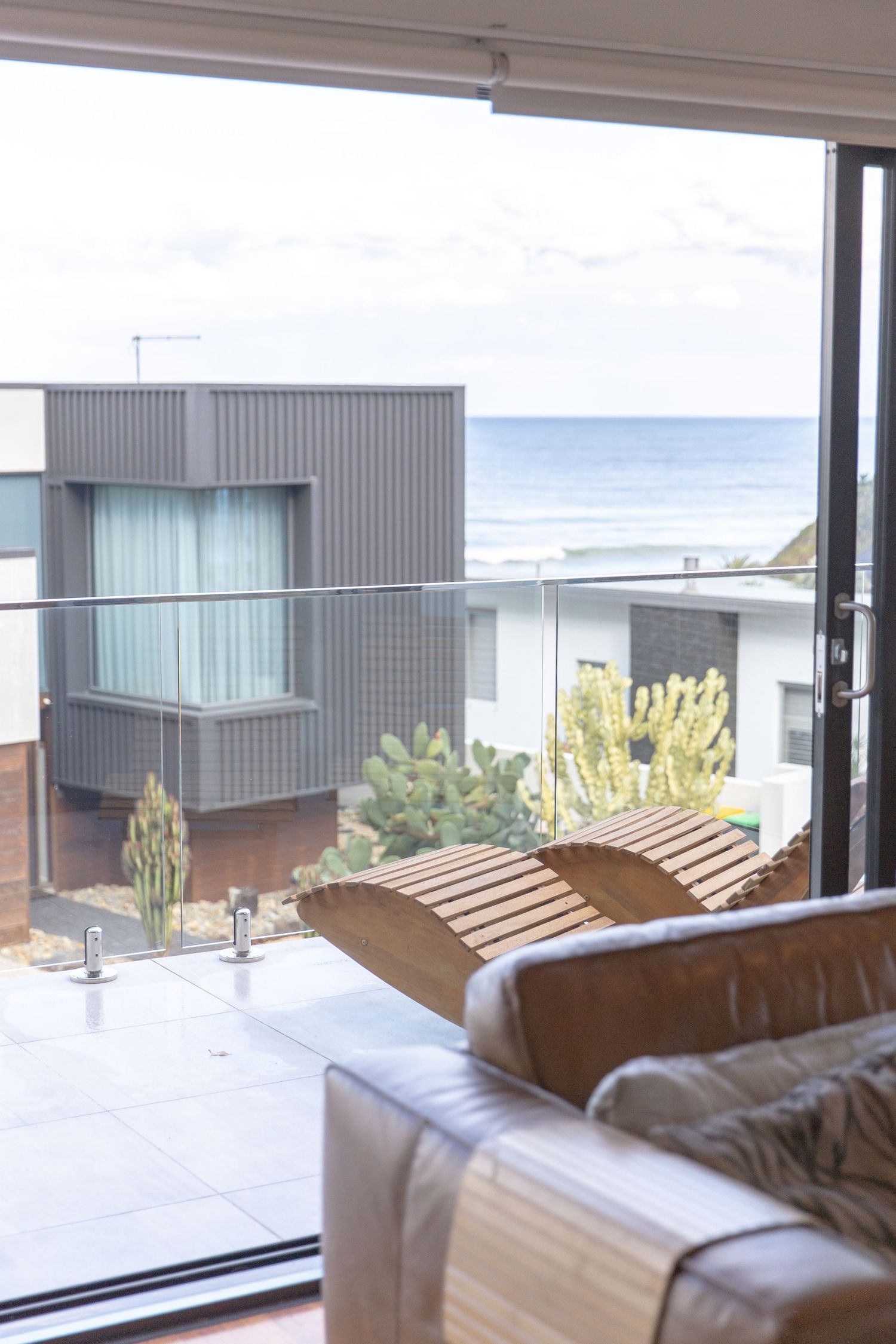 Modern coastal apartment interior with ocean views and contemporary furnishings visible through large windows.